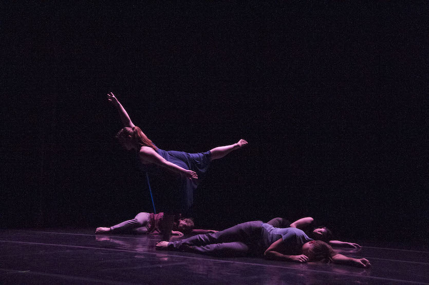 Photo of dancers performing on stage with a dark background
