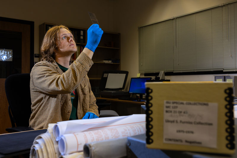 Brady Cooke, student and Career Path Intern for Idaho State University, views a negative from the Lloyd S. Furniss collection used as part of a Ken Burns’ documentary “The American Buffalo.” The collection was donated by the family of Furniss to ISU’s Special Collections and Archives.