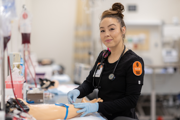 Practical nursing student administers an IV to a training manikin arm