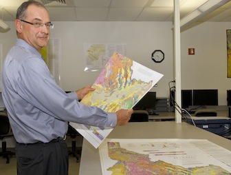 Paul Link with a folded  map in his hand, and a unfolded map on the table. (ISU Photographic Services)